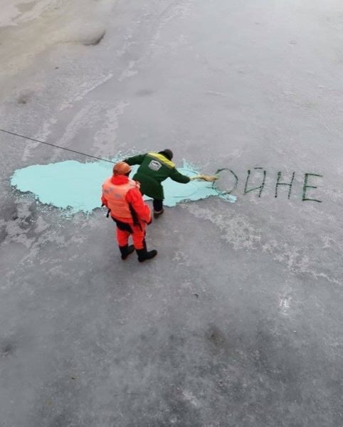 Коммунальщики закрашивают антивоенный призыв на люду притока Невы в Санкт-Петербурге
